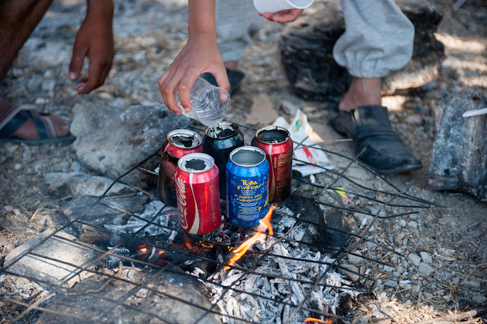 Syrian refugees using empty cans of coke to boil water for their tea in Kara Tepe camp