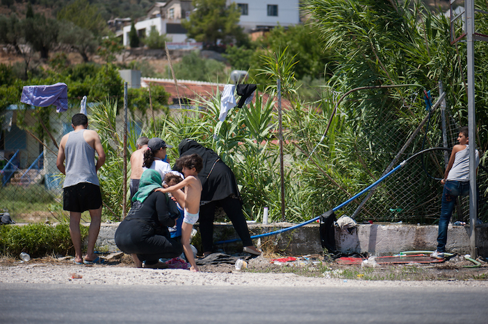 A refugee family washes by the main road outside the Kara Tepe camp. There are few water taps  in the camp