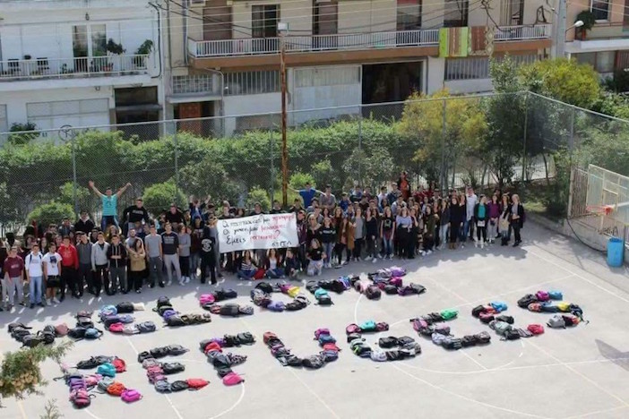 Students at an Athens high school make the words "Welcome Refugees" out of their book bags.