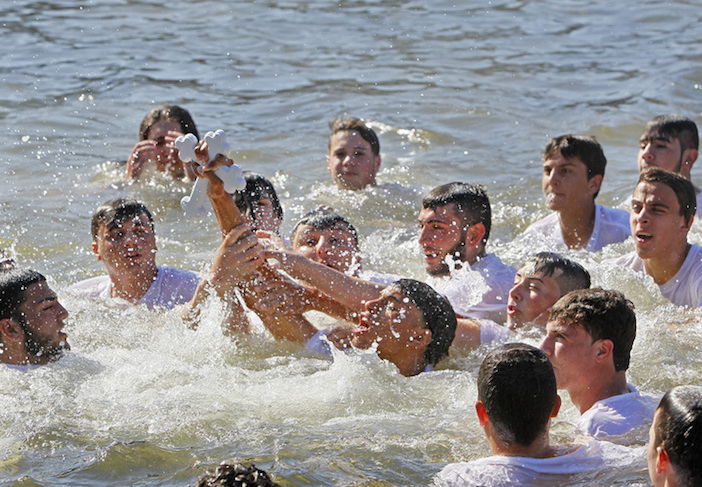 Joseph Cooley, 18, of Tarpon Springs holds up the cross after retrieving it from Spring Bayou during Tarpon Spring's 111th annual celebration of Epiphany. Photo from www.tampabay.com