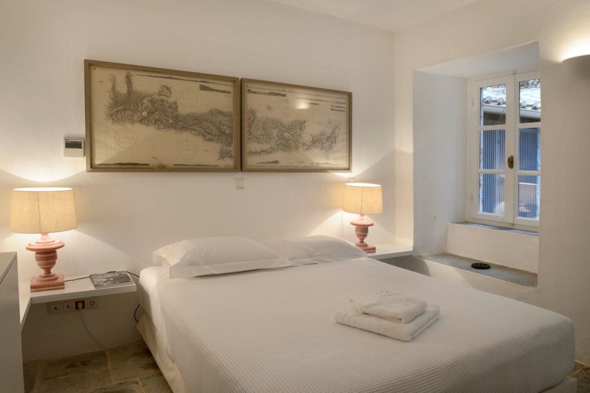 Bedroom at the Patrick and Joan Leigh Fermor House with historic maps above the bed