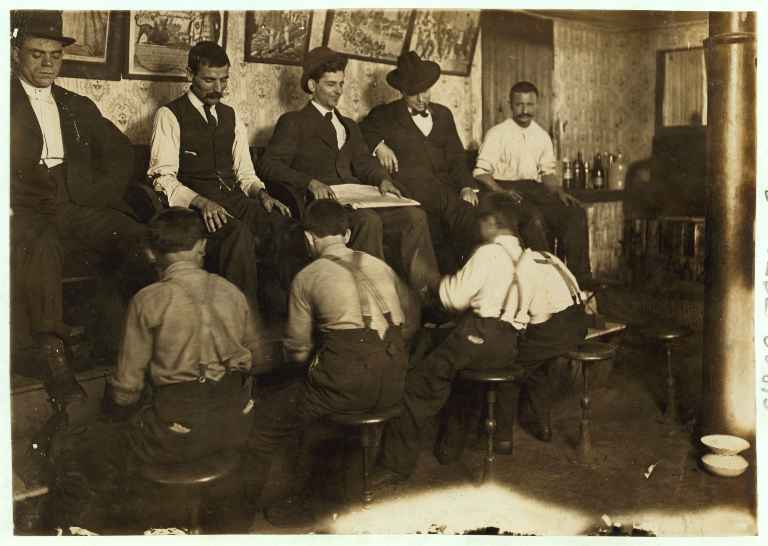 Four young Greek bootblacks shining customers' shoes inside an Indianapolis parlor in 1908