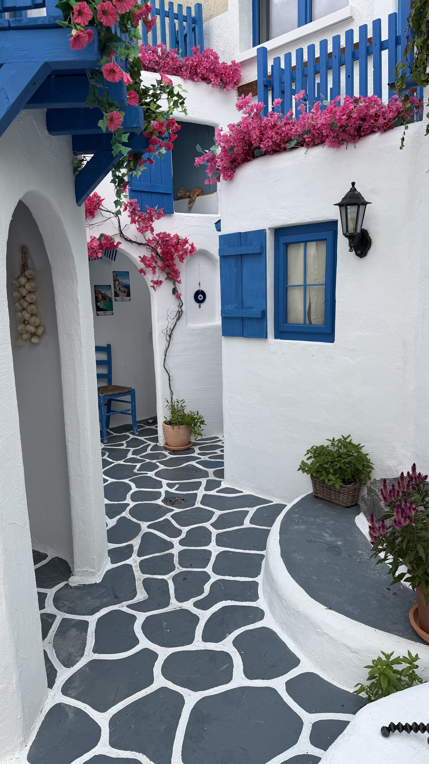Blue shutters and bougainvillea in a whitewashed lane inside Little Greece