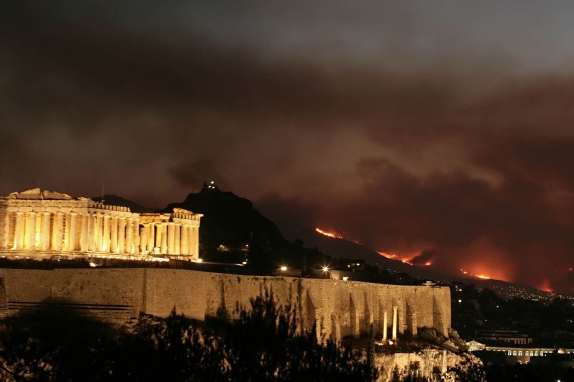 Wildfire burning on hills behind the illuminated Acropolis in Athens