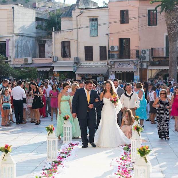 In the old town of Hania, the couple walks on the flowered pathway as family and friends watch.